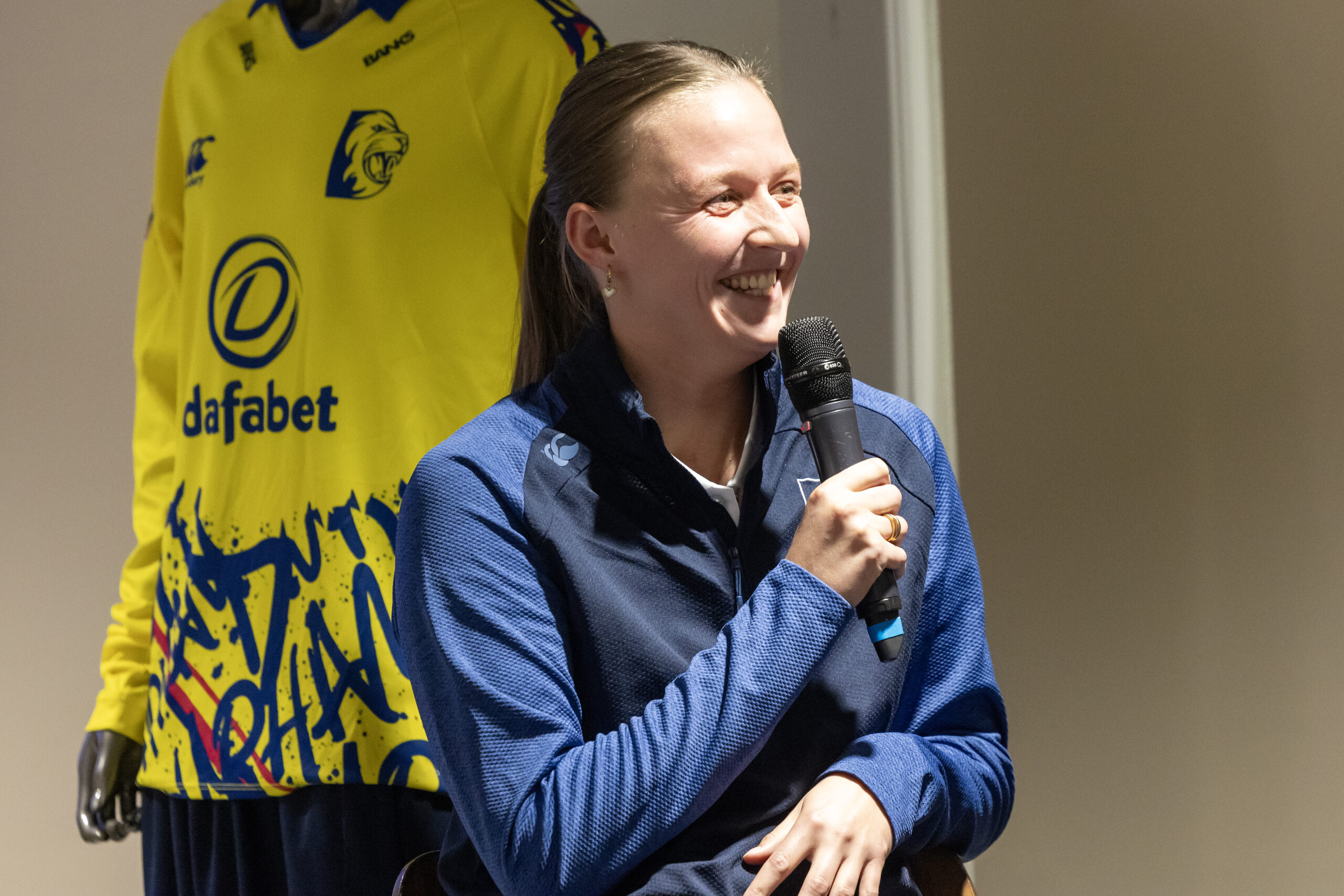 A woman cricketer holding a microphone