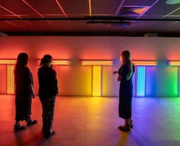 People standing at the Light exhibition with rainbow colours in the background